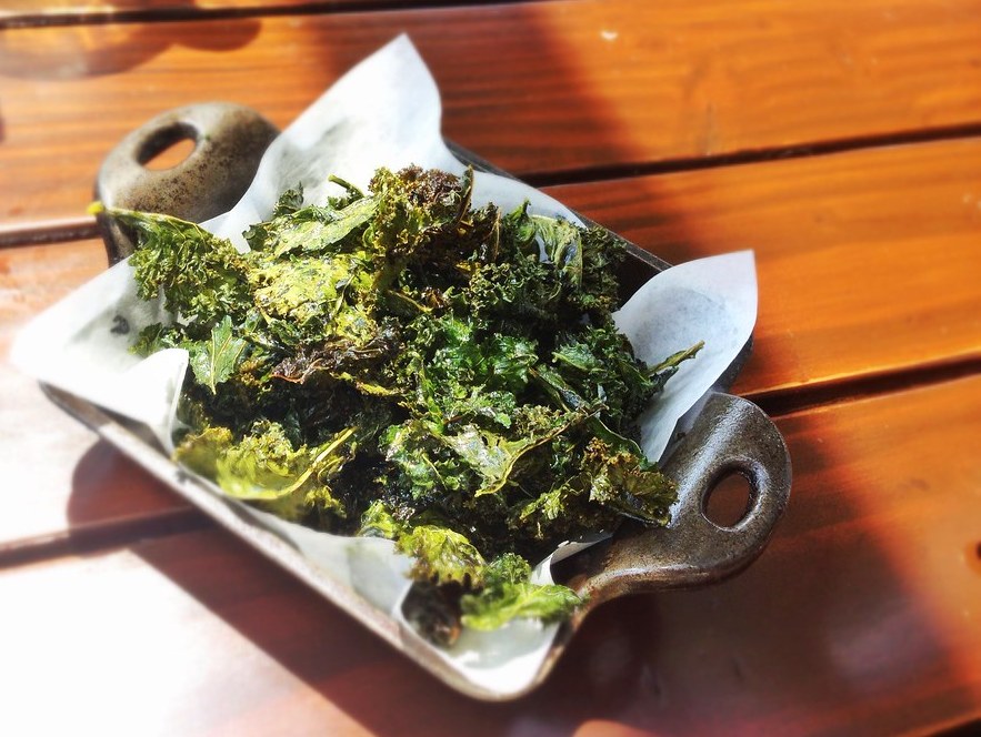 Kale Chips served on parchment paper in a cast iron skillet.