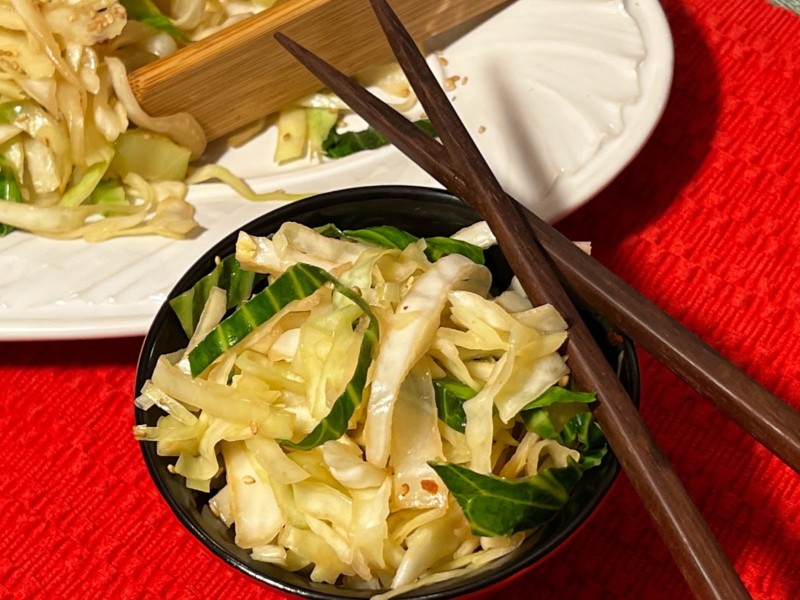 Cabbage stir fry in a bowl with chop sticks resting on top