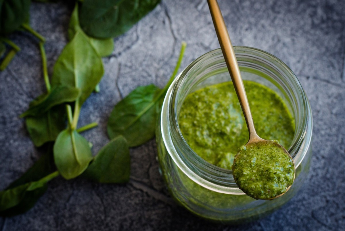 Jar of basil pesto with a spoon on top