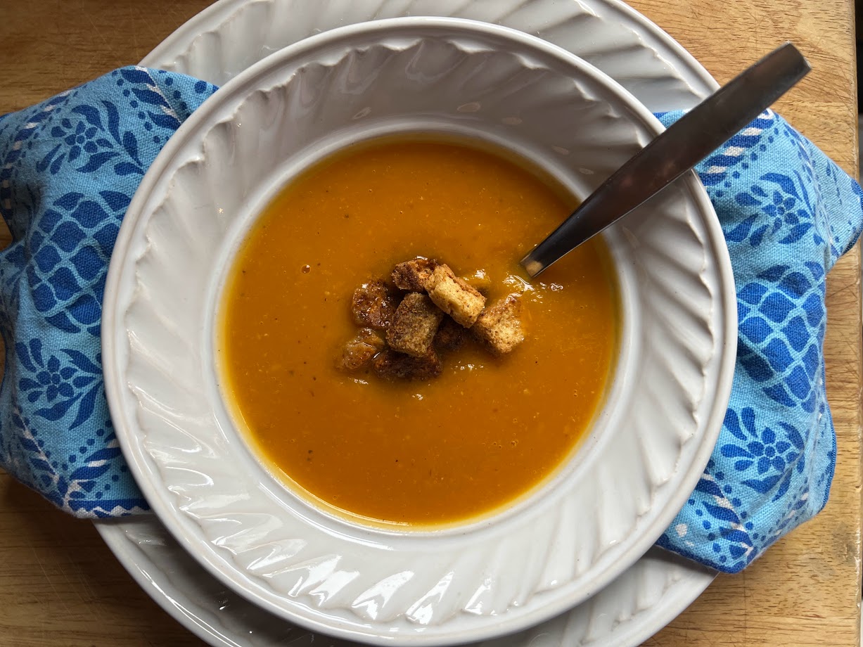 A bowl of butternut squash soup topped with croutons