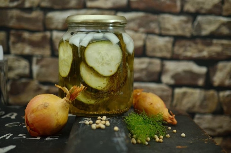 Pickle slices in a glass jar with onions and seasoning