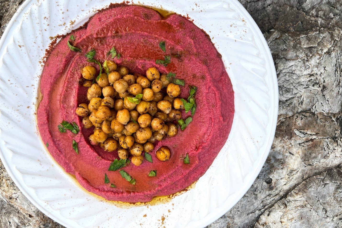 Photo of white plate with Beet Hummus, drizzled with olive oil and topped with pan roasted chickpeas