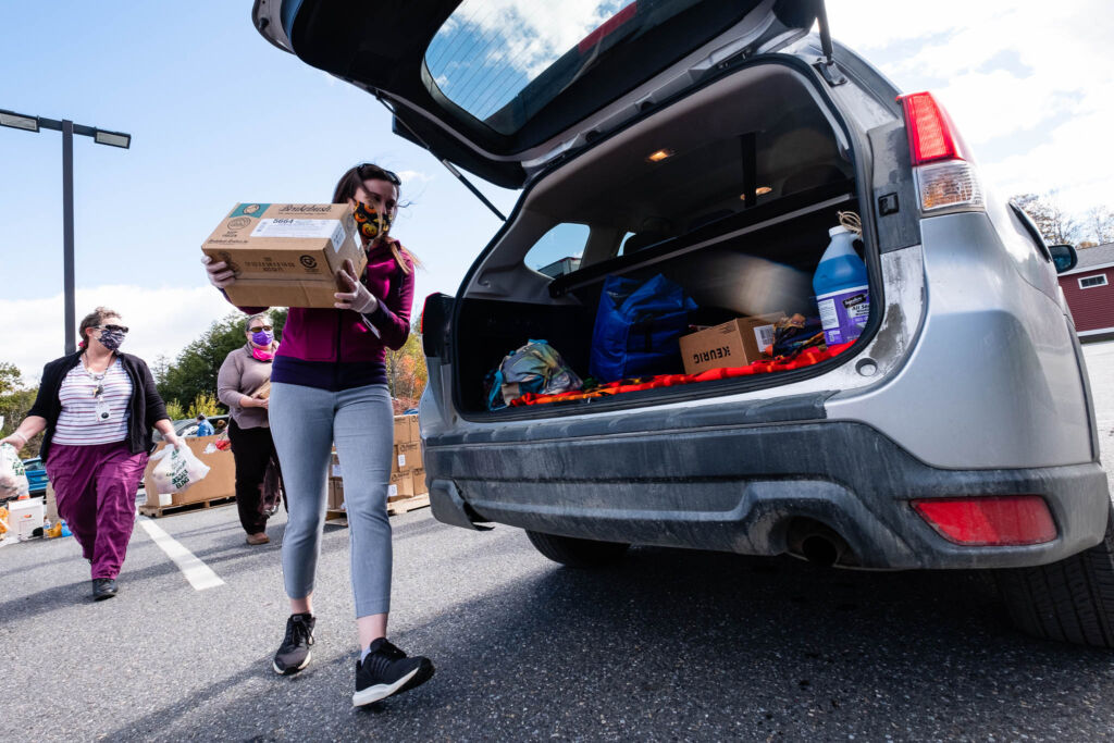 A volunteer loads a box of food into the back of a car at a produce distribution. The Foodbank has adopted new volunteer screening practices to make this program more inclusive.