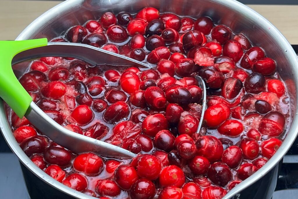 Photo of popped cranberries being lightly mashed in saucepan